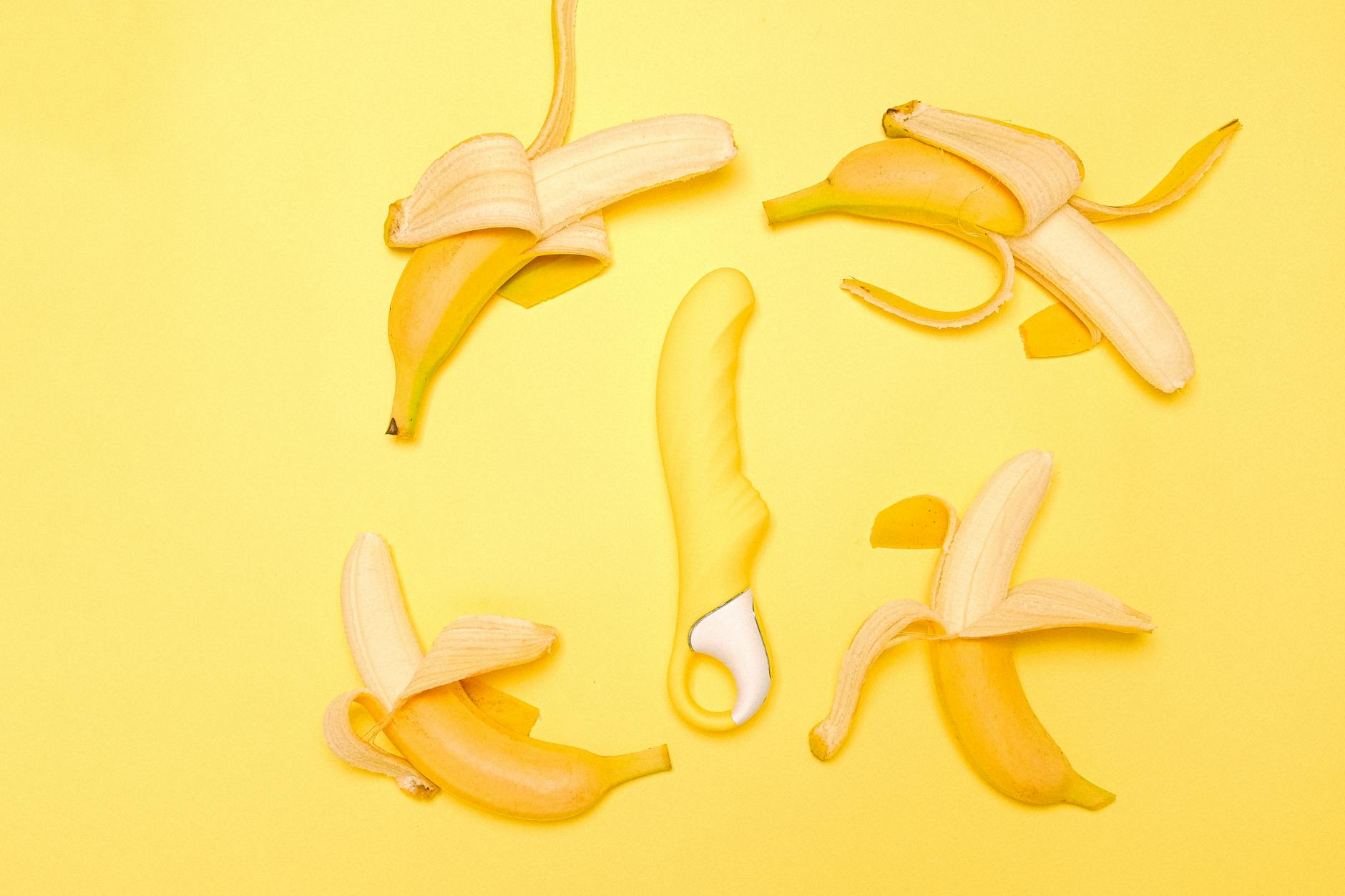 Yellow lemon clitoral vibrator with fresh lemons on a bright background