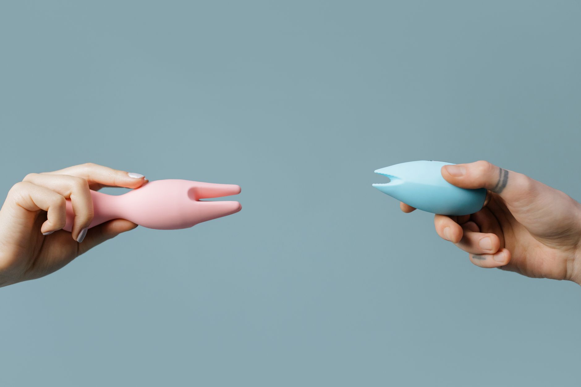 Two hands holding silicone vibrators demonstrating different stimulation techniques