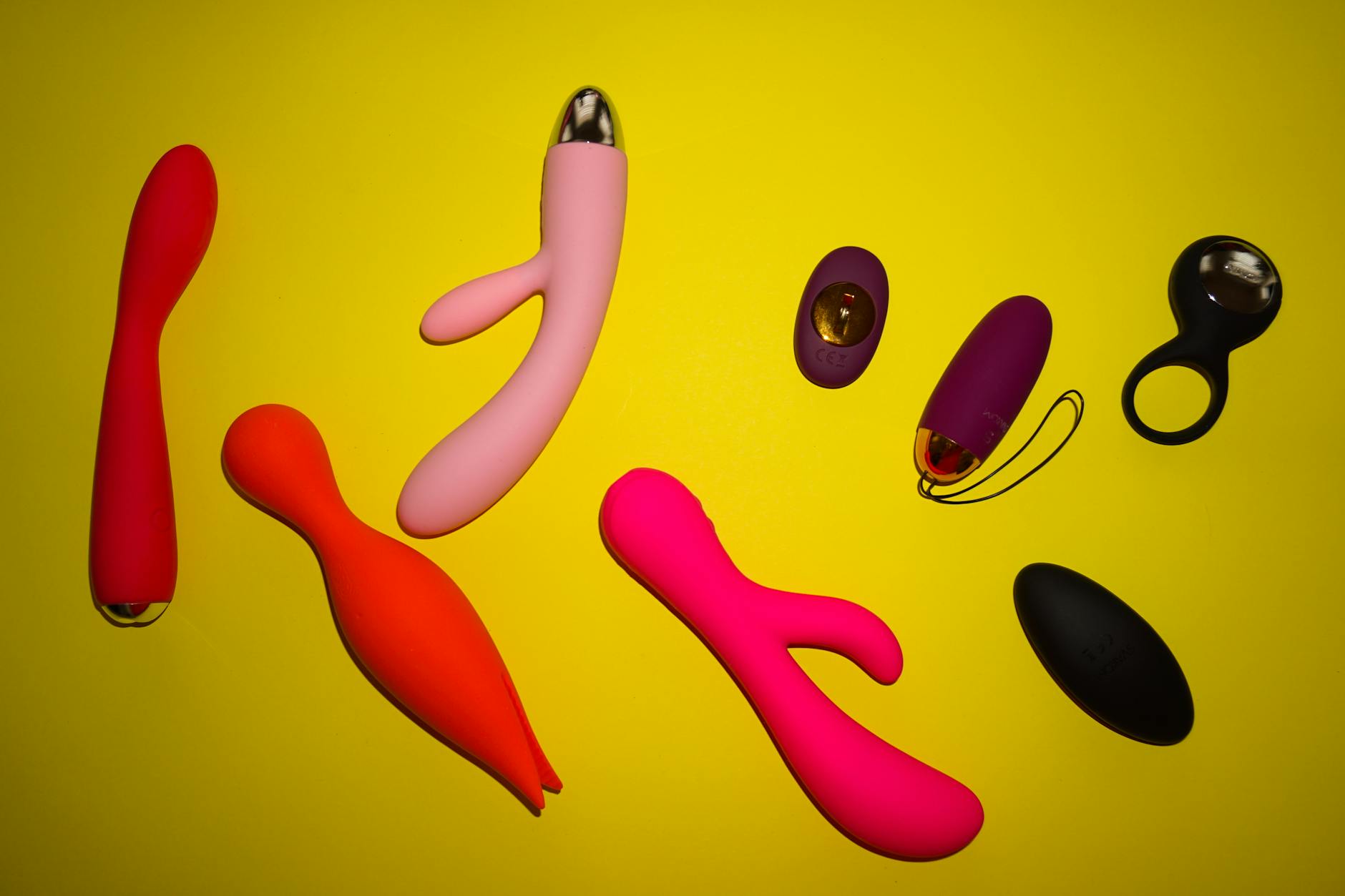 Vibrant sex toys arranged on a bright yellow surface, symbolizing diverse pleasure tools for long-term couples